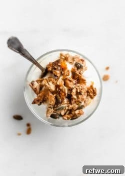 A top-down view of a cup of yogurt topped with orange cardamom tahini granola, emphasizing its crunchy texture.