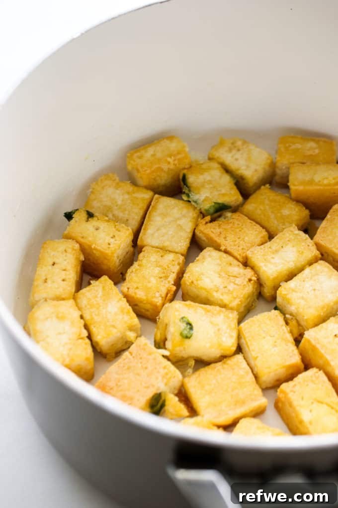 Close-up of perfectly browned and crispy tofu cubes in a pan, showcasing their irresistible texture.