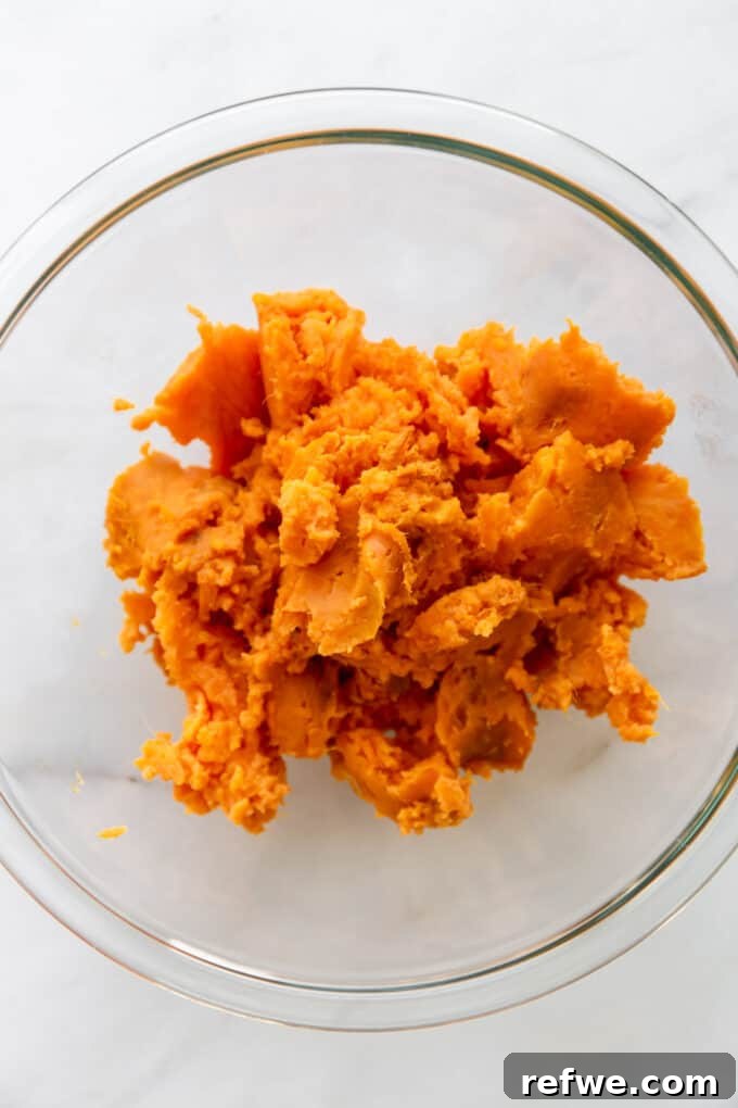 Scooped sweet potato flesh in a clear mixing bowl, ready to be mashed.