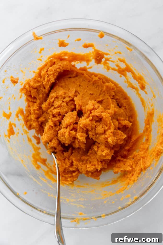 Smooth, mashed sweet potatoes in a clear mixing bowl, perfectly blended.