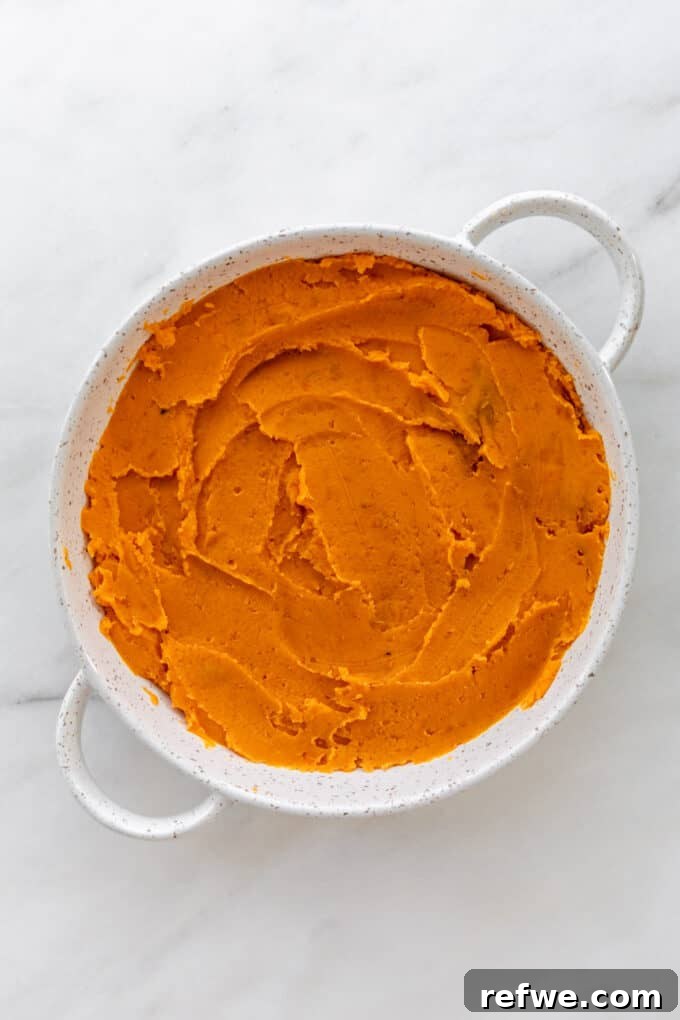 Mashed sweet potatoes spread evenly in a round serving dish, forming the casserole base.