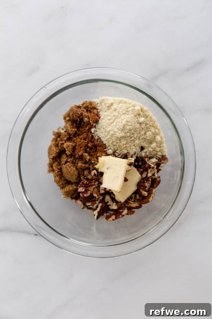 A bowl containing chopped pecans, vegan butter, coconut sugar, and almond flour, ingredients for the crumble topping.
