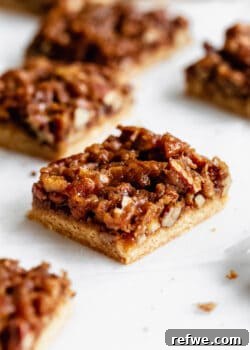 Close-up of a perfectly sliced healthy pecan pie bar, showcasing its golden crust and rich, gooey pecan topping.