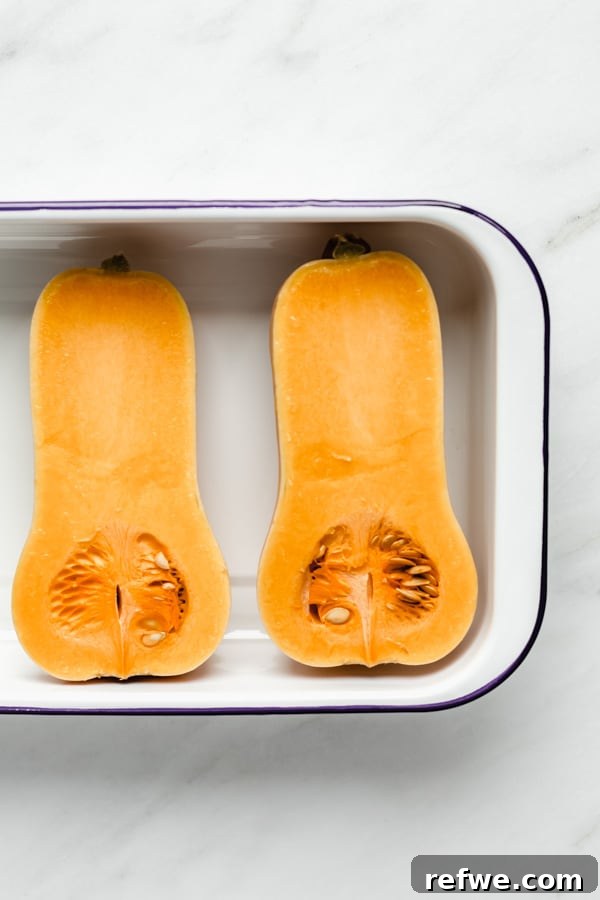 Mastering Butternut Squash Cooking 4 Two halves of raw butternut squash placed in a white roasting pan, ready for cooking
