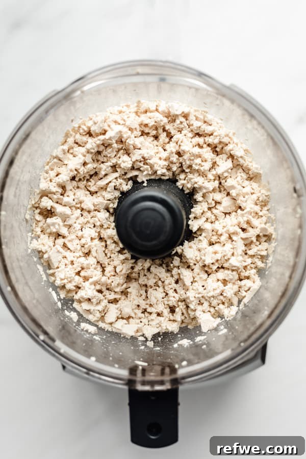 Easy Chipotle Copycat Tofu Sofritas 4 Crumbled tofu in a food processor, showing the ideal textured consistency for homemade sofritas after careful pulsing.