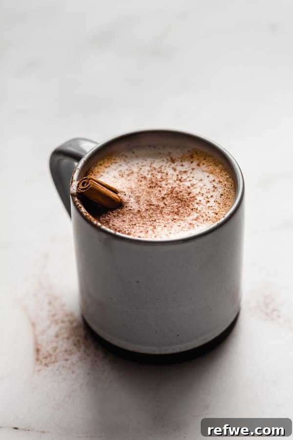 Warm Vegan Pumpkin Spice Delight 5 A charming blue and grey ceramic mug holds a luscious pumpkin spice latte, beautifully topped with a sprinkle of cinnamon, capturing the essence of a perfect Fall drink.