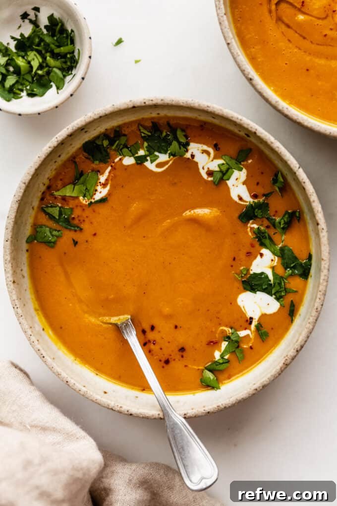 Warming Roasted Sweet Potato Carrot Ginger Soup 2 A bowl of sweet potato carrot and ginger soup topped with cilantro and yogurt