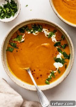 Warming Roasted Sweet Potato Carrot Ginger Soup 10 A bowl of sweet potato carrot and ginger soup topped with cilantro and yogurt
