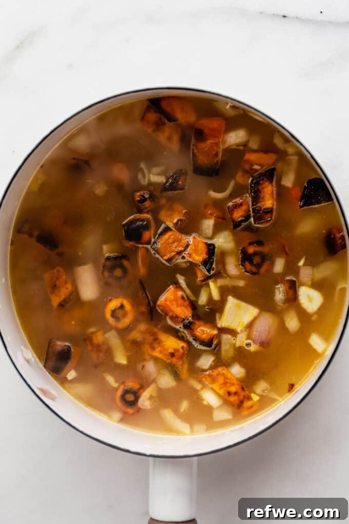 Warming Roasted Sweet Potato Carrot Ginger Soup 7 vegetable broth, sweet potatoes and carrots in a white pot