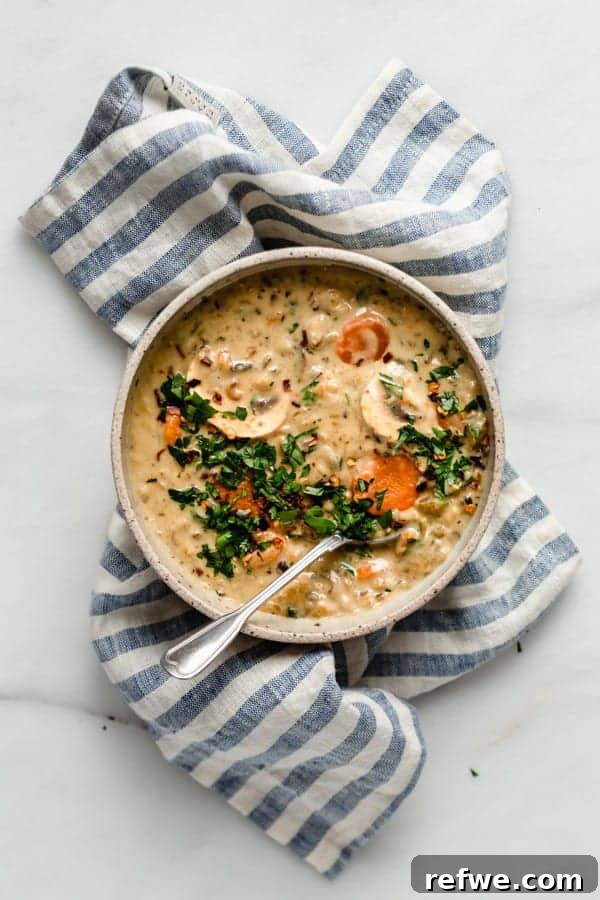 Creamy Instant Pot Wild Rice Comfort 2 A vibrant bowl of creamy Instant Pot Wild Rice Soup, garnished with fresh herbs, resting on a blue striped napkin.
