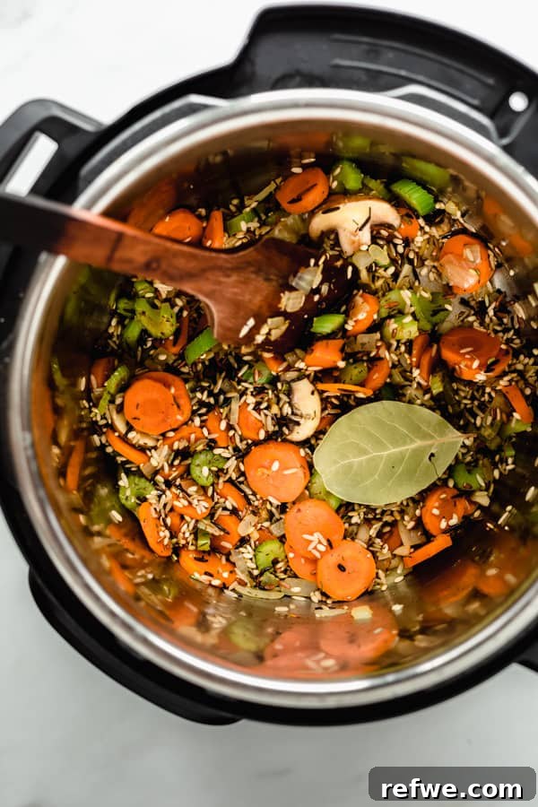 Creamy Instant Pot Wild Rice Comfort 3 Instant Pot filled with sautéed vegetables and wild rice, ready for broth.
