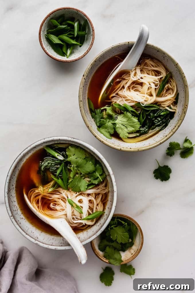 Aromatic Vegan Pho 7 Two enticing bowls of vegan pho soup, artfully arranged with silky rice noodles and crisp bok choy, awaiting the final flourish of fresh herbs and condiments.