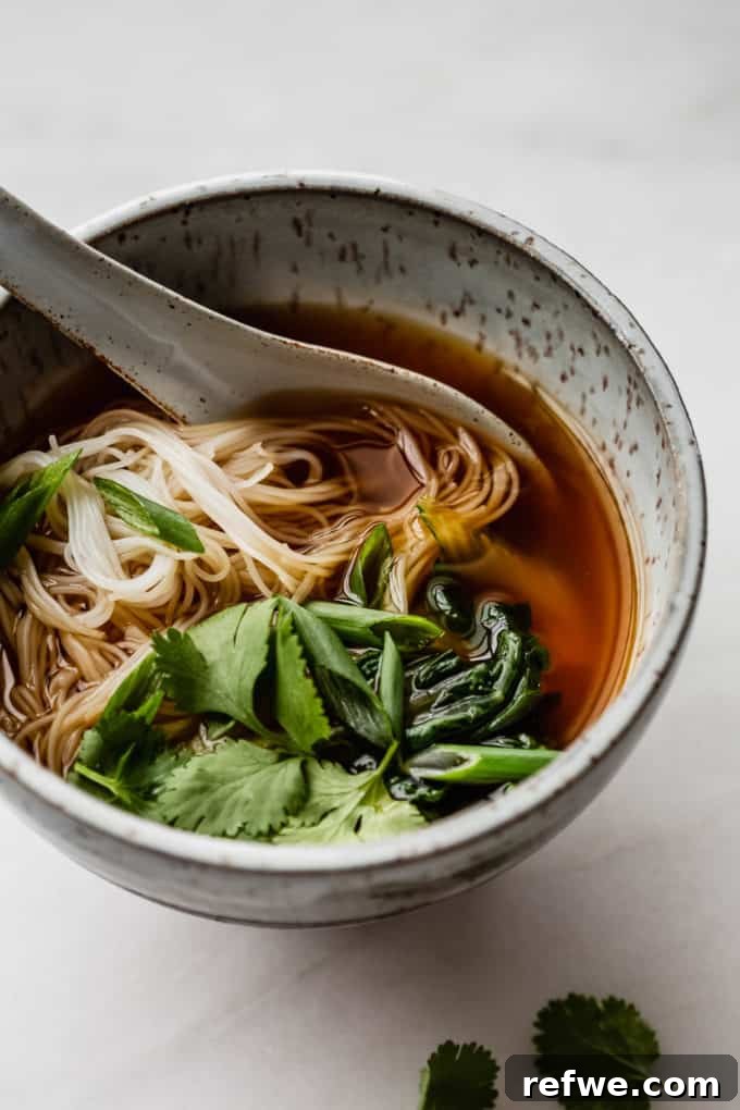 Aromatic Vegan Pho 9 A close-up of a beautifully textured speckled blue ceramic bowl filled with steaming vegan pho, showcasing its vibrant ingredients and inviting warmth.