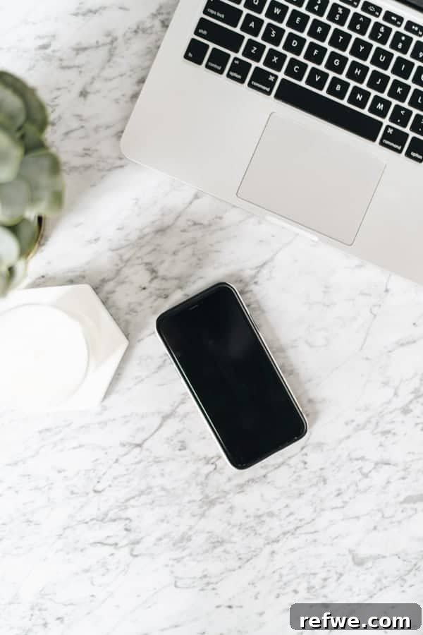 An iPhone and laptop arranged on a marble table, symbolizing digital presence and connectivity.