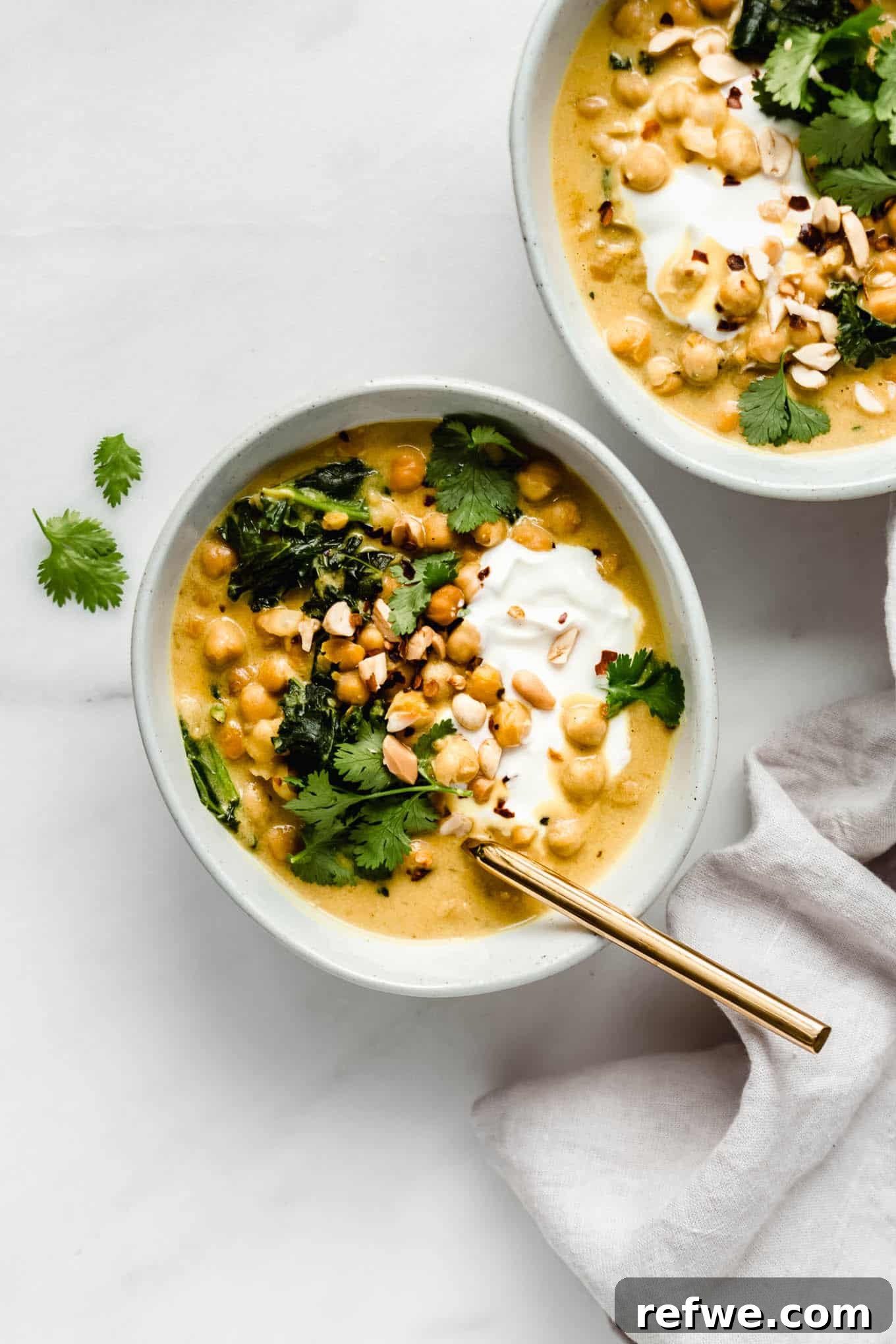 Creamy Coconut Chickpea Stew 2 A vibrant bowl of Coconut Chickpea Curry, garnished with fresh cilantro and a gold spoon, inviting you to dig in.
