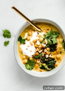 A bowl of rich coconut chickpea curry topped with creamy yogurt, crunchy peanuts, and fresh cilantro, inviting a delightful meal.