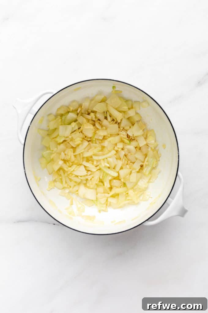 Creamy Coconut Chickpea Stew 4 A white pot containing sautéed onions, forming the aromatic base for the curry.