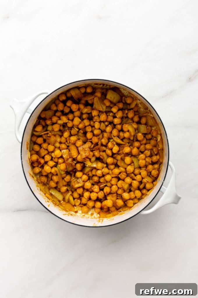 Creamy Coconut Chickpea Stew 6 A white pot with chickpeas, curry paste, and spices cooking to deepen their flavor.