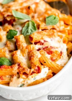 A close up of baked ziti topped with cheese and basil leaves