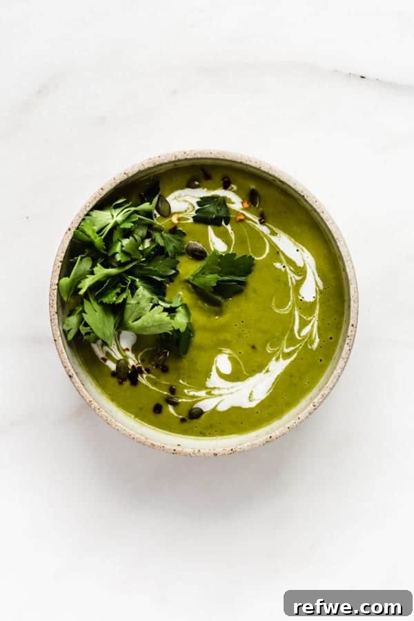 A vibrant bowl of creamy broccoli soup, garnished with a swirl of coconut milk and fresh parsley, against a rustic background.