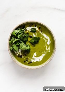 A bowl of creamy broccoli soup topped with coconut milk and fresh parsley