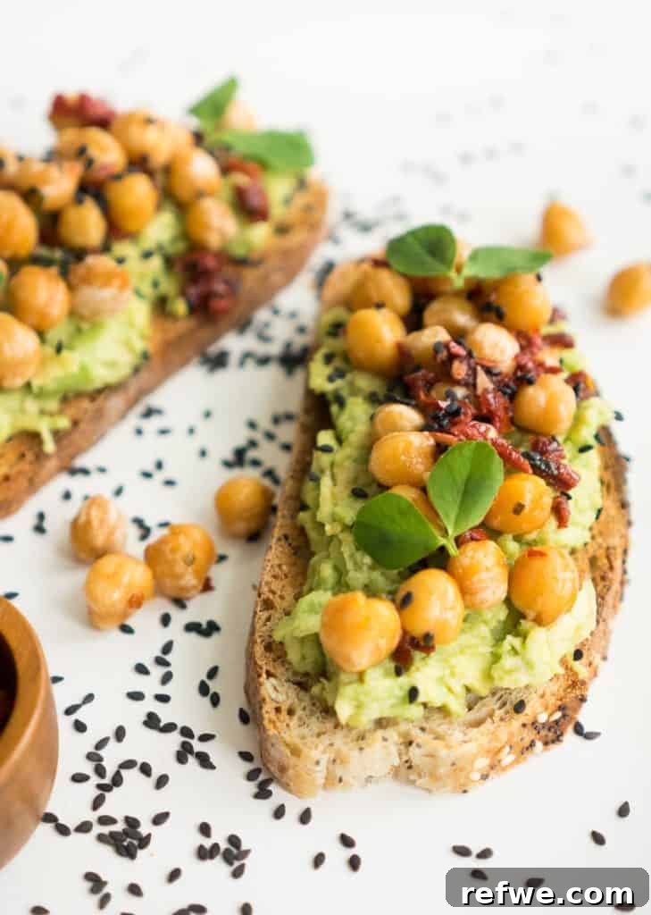 Quick Nutritious Morning Meals 13 chickpeas on top of avocado toast, topped with black sesame seeds on a white plate