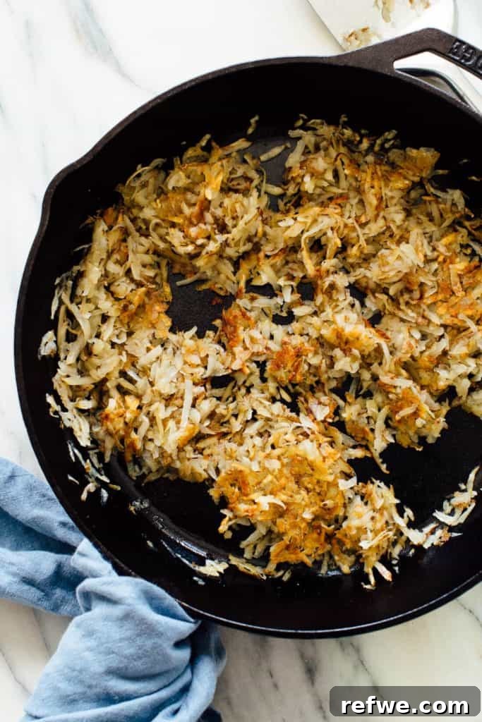 Quick Nutritious Morning Meals 3 shredded hash browns being cooked in a cast iron skillet