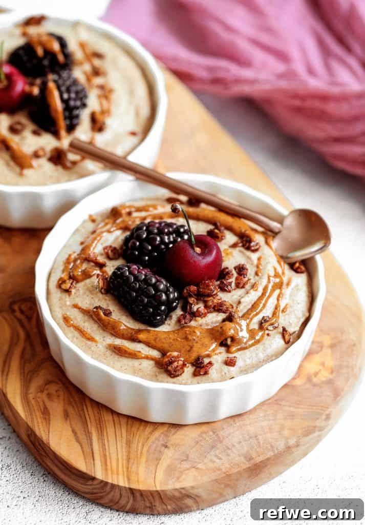 Quick Nutritious Morning Meals 21 cherries and blackberries on top of a white ramekin filled with healthy breakfast pudding, drizzled with almond butter on top of a wooden board