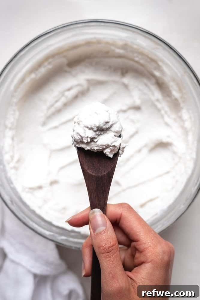 Quick Nutritious Morning Meals 8 hand holding a wooden spoon of coconut yogurt over the large glass bowl of yogurt