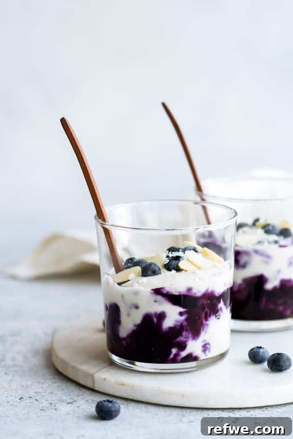 Quick Nutritious Morning Meals 9 jars of blueberry cheesecake with wooden spoons on top, on top of a wooden board with blueberries and a white napkin