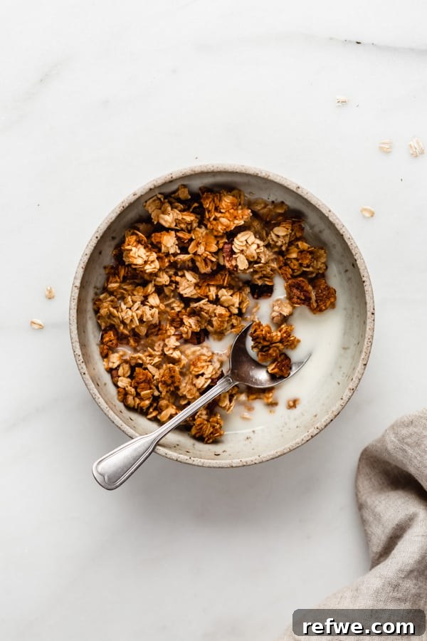 Spiced Banana Bread Granola 8 A bowl of banana bread granola served with almond milk, accompanied by a neatly folded napkin, highlighting a perfect breakfast setup.