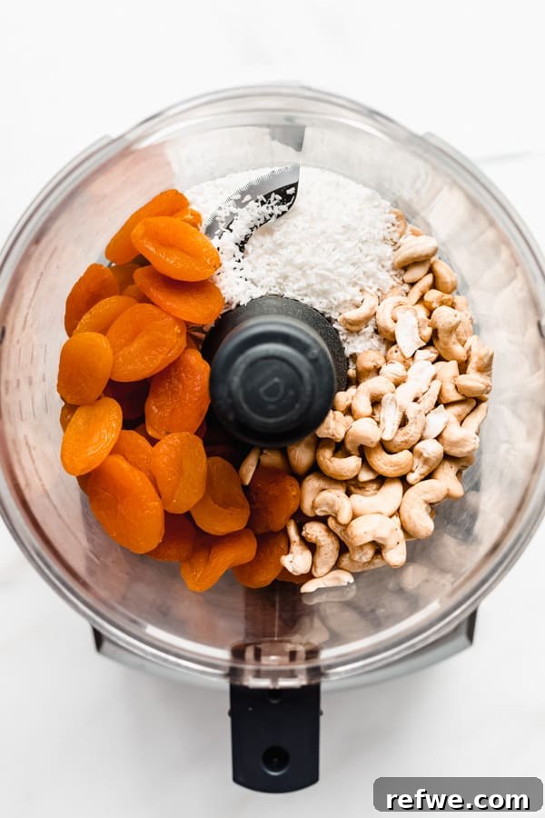 Sun Kissed Apricot Coconut Power Bites 3 A mix of apricots, cashews, and coconut being processed in a food processor, transforming into a sticky dough.