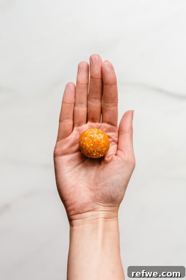 Sun Kissed Apricot Coconut Power Bites 5 Hands rolling the apricot mixture into small, uniform energy balls, preparing them for coating.