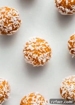 An individual Coconut Apricot Energy Ball, coated in shredded coconut, showcasing its delicious texture.
