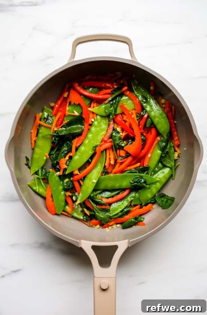 Quick Healthy Vegetable Lo Mein 6 A pan with snow peas, peppers, carrots and spinach in it