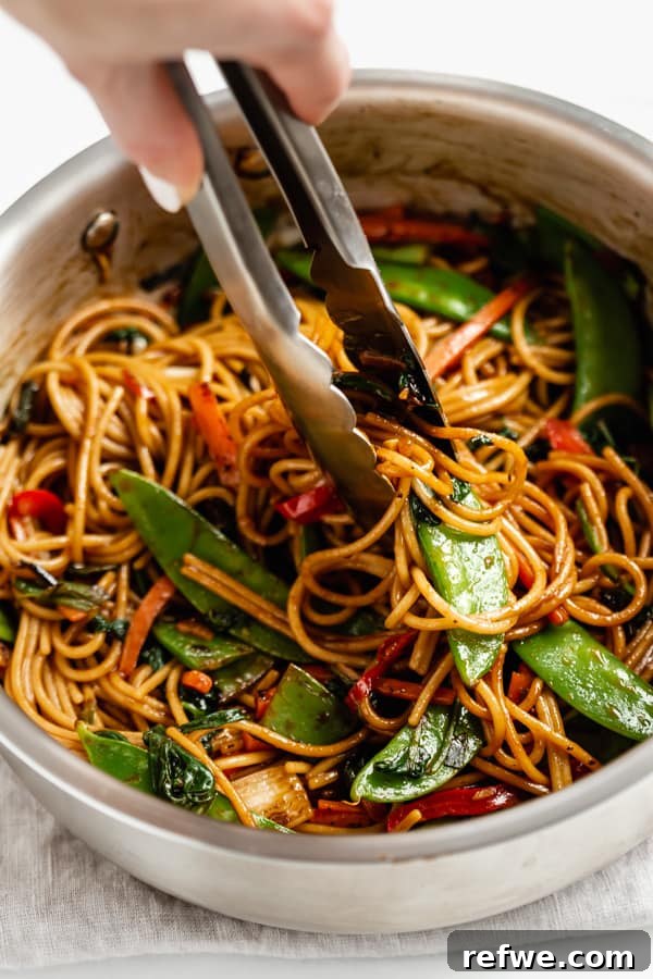 Quick Healthy Vegetable Lo Mein 10 tongs scooping up vegetable lo mein from a pan