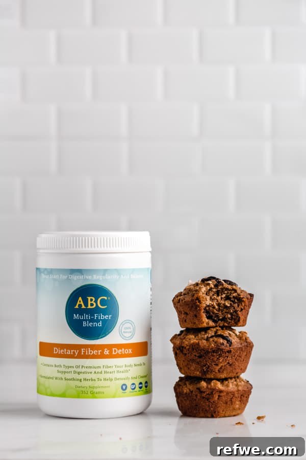 Portable Oat Cups 9 A bottle of nutritional brand fiber blend sits alongside a stack of three perfectly baked oatmeal cups, highlighting the healthy addition to the recipe.