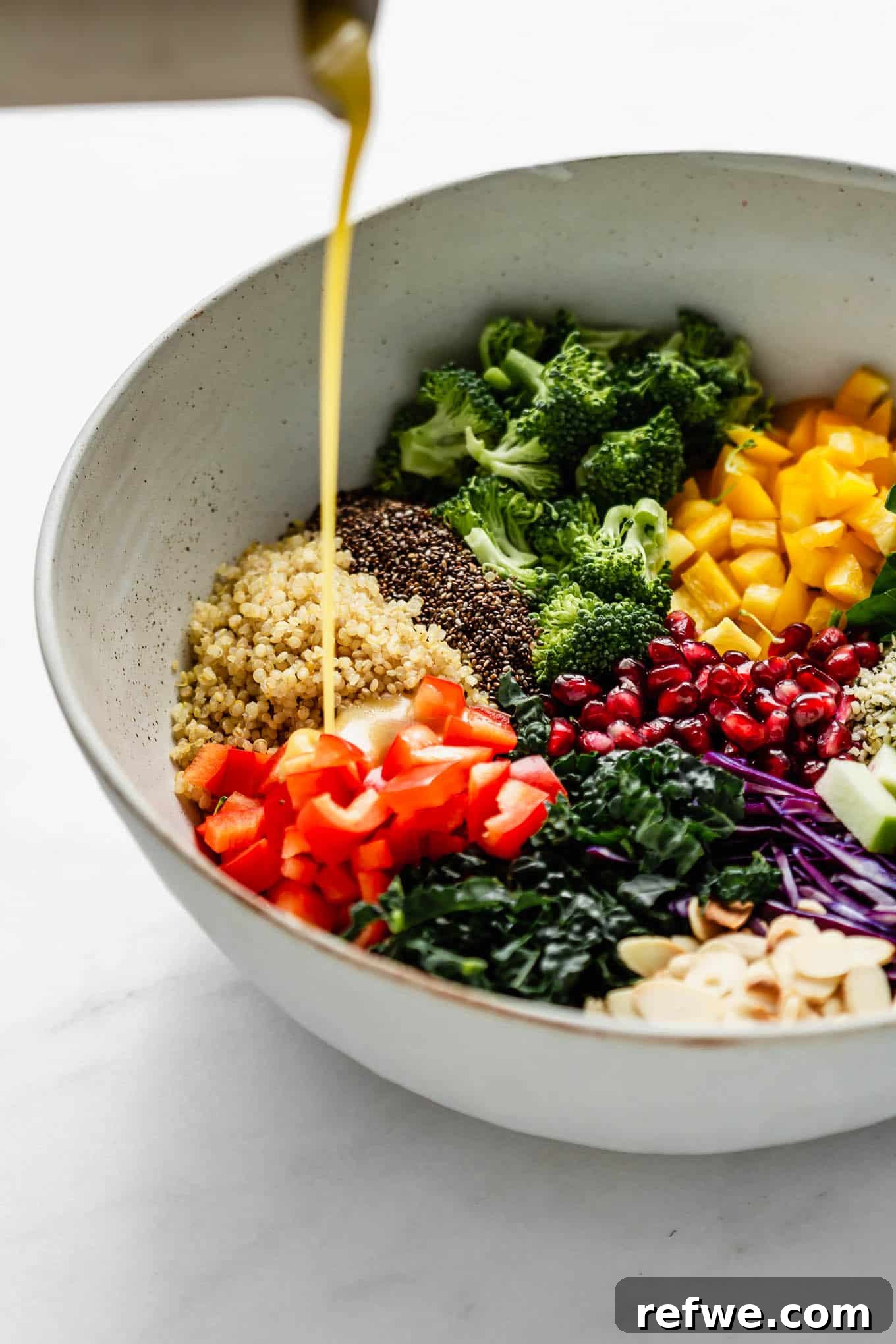 Vibrant Vitality Bowl 4 Maple vinaigrette being drizzled generously over a fresh bowl of Superfood Salad.