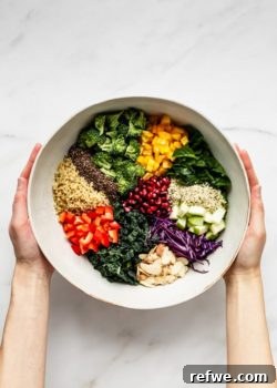 Two hands holding a bowl of chopped vegetables and cooked quinoa, preparing the Superfood Salad.