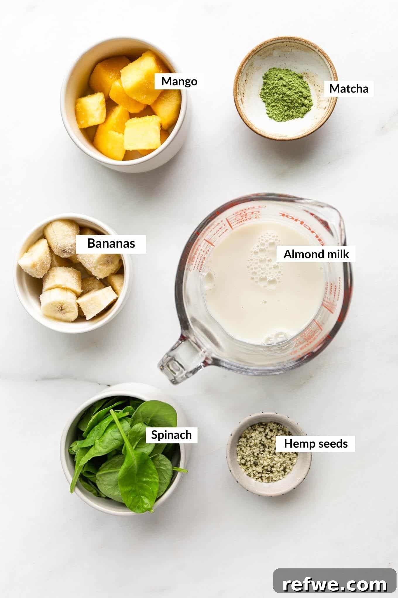 Vibrant Matcha Smoothie 3 A vibrant selection of ingredients including fresh spinach, frozen mango, bananas, matcha powder, and hemp seeds, arranged for making a smoothie.