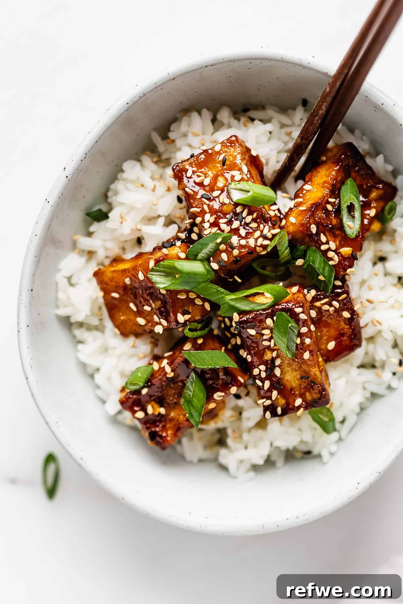 Zesty Crispy Tofu Sheet Pan Delight 2 Delicious Crispy Orange Tofu served in a bowl, garnished with green onions and sesame seeds.