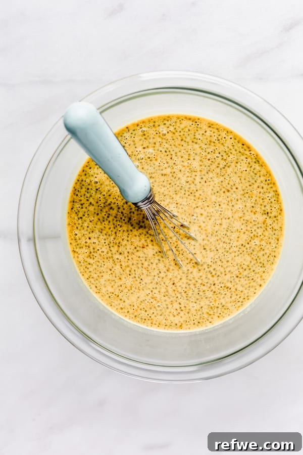 Golden Glow Chia Pudding 7 A clear mixing bowl holding the partially mixed chia pudding with a whisk still in it, showing the early stages of thickening.