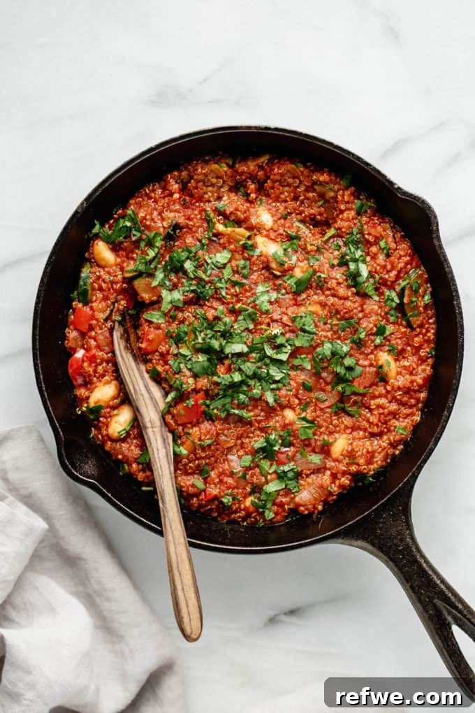 Hearty Vegan Shakshuka 7 A finished vegan quinoa shakshuka, served hot and inviting in a cast iron skillet with a wooden spoon, garnished and ready to be enjoyed.