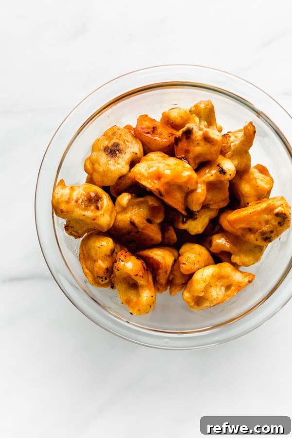 Buffalo Cauliflower Bites 5 A clear mixing bowl filled with golden-brown baked cauliflower wings.