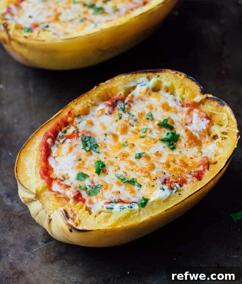 Close-up of a halved Vegetarian Lasagna Stuffed Spaghetti Squash, showing layers of ricotta, spinach, sauce, and melted mozzarella