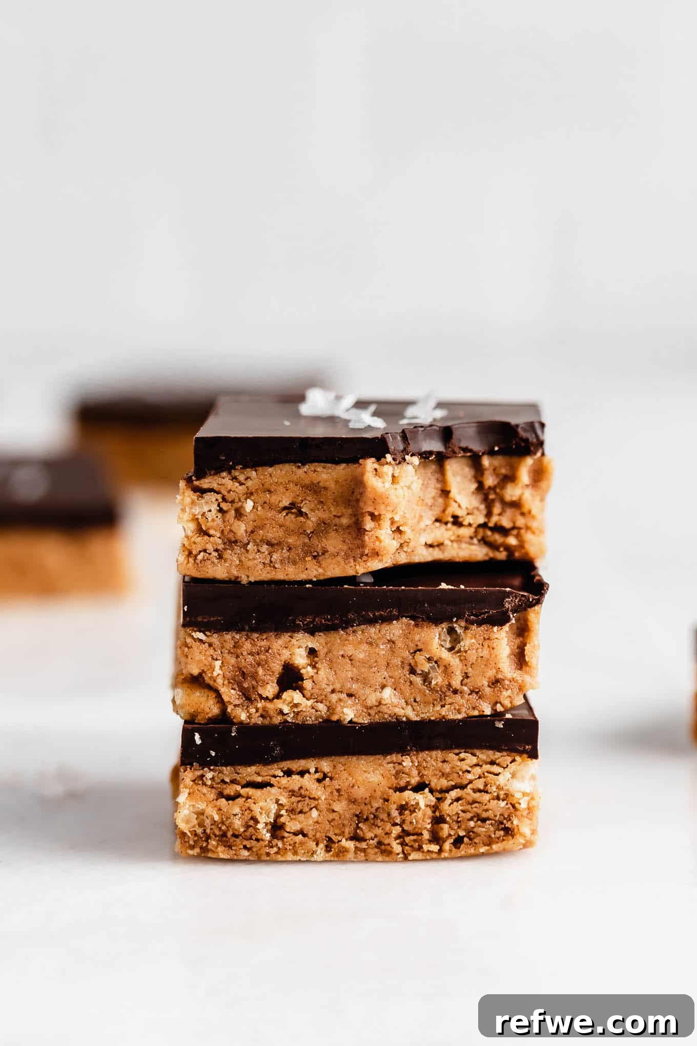Decadent Chocolate Peanut Butter Muscle Bars 2 A stack of three homemade chocolate peanut butter protein bars with a chocolate drizzle.