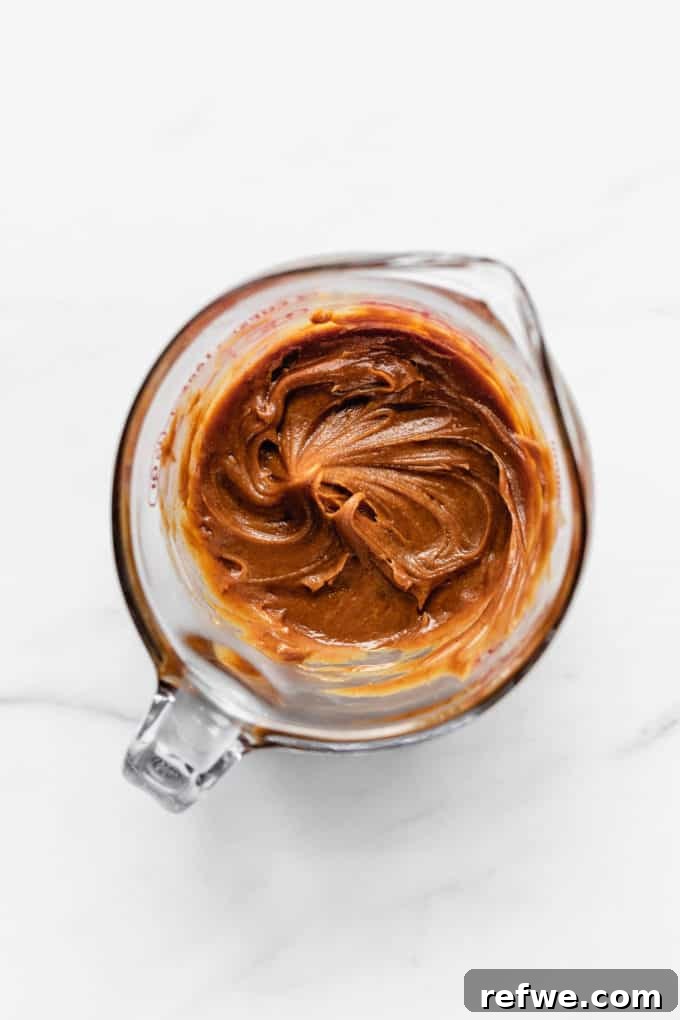 Decadent Chocolate Peanut Butter Muscle Bars 5 Creamy peanut butter in a measuring cup, ready to be mixed with other wet ingredients.