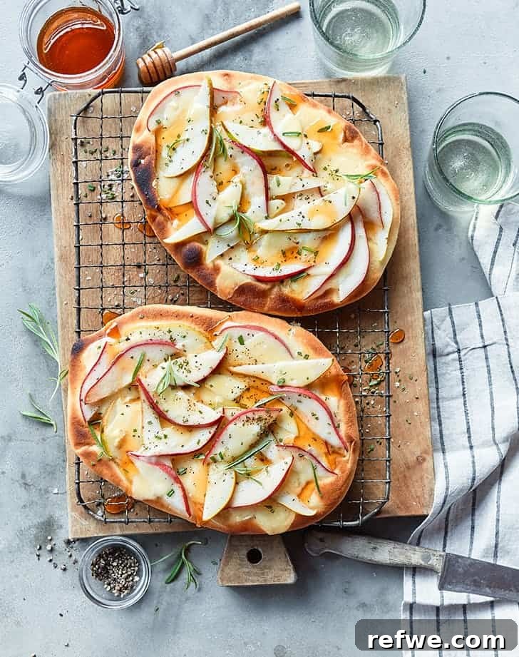 Effortless Elegance: 20 Stunning Date Night Dinners 11 Gourmet pear, brie, and rosemary flatbreads, artfully arranged on a wooden platter and surrounded by fresh herbs, set against a blue backdrop with a silver knife, perfect for sharing on date night.