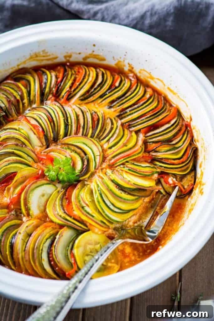 Effortless Elegance: 20 Stunning Date Night Dinners 13 Elegant ratatouille featuring thinly sliced vegetables (zucchini, eggplant, tomato) arranged in concentric circles, covered in flavorful tomato sauce, served in a white dish with a silver serving fork.