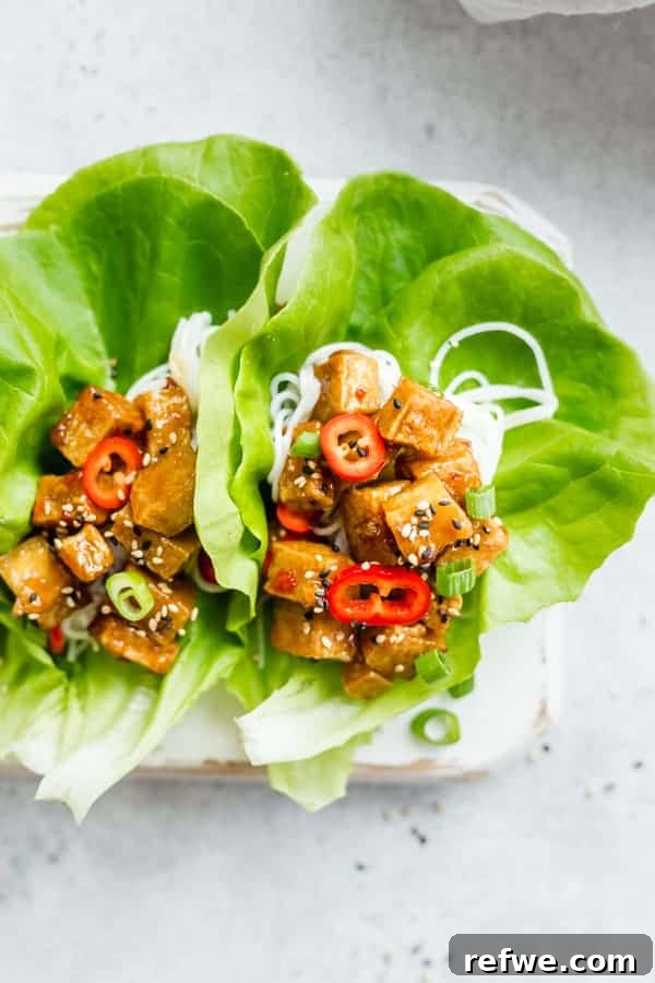Effortless Elegance: 20 Stunning Date Night Dinners 4 Vibrant sweet chili tofu with green onions and colorful peppers, nestled in crisp butter lettuce cups, served with rice noodles on a plate against a grey backdrop.